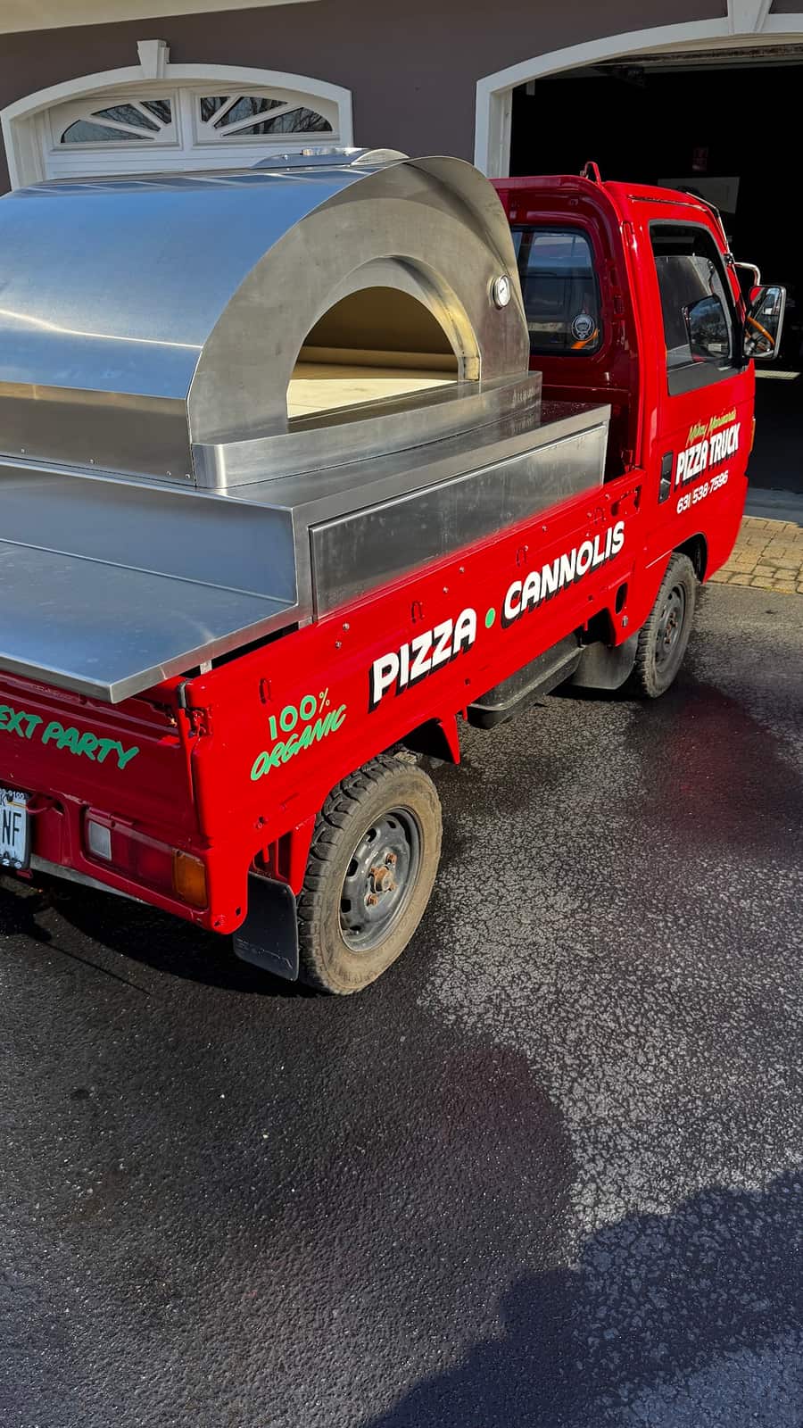 The rear of the pizza truck showing the wood-fired oven and the stainless prep counter