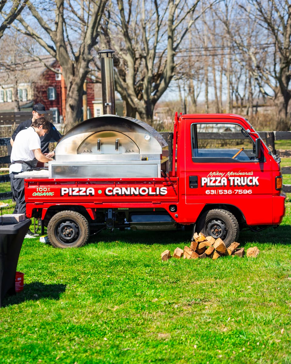 Cooks working the wood-fired oven on the truck at a lawn event