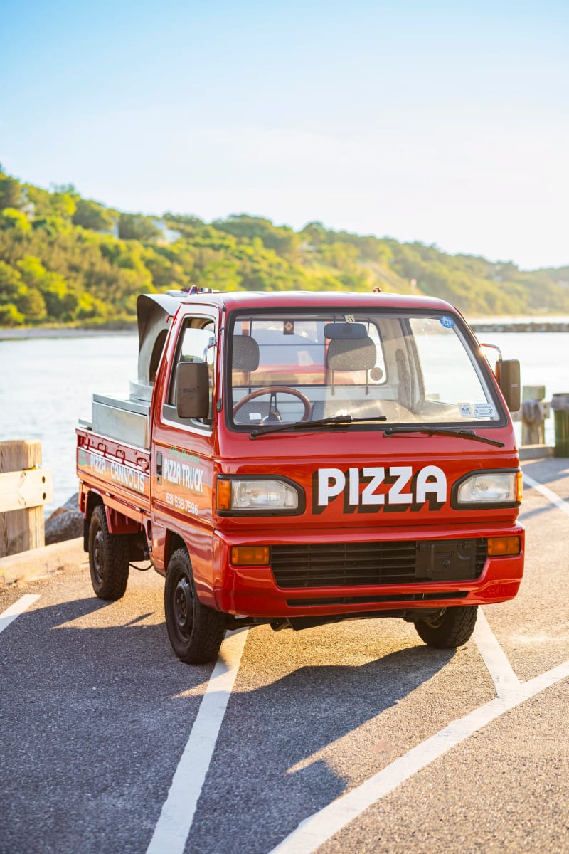 The red pizza truck parked nose-on at a Long Island harbor