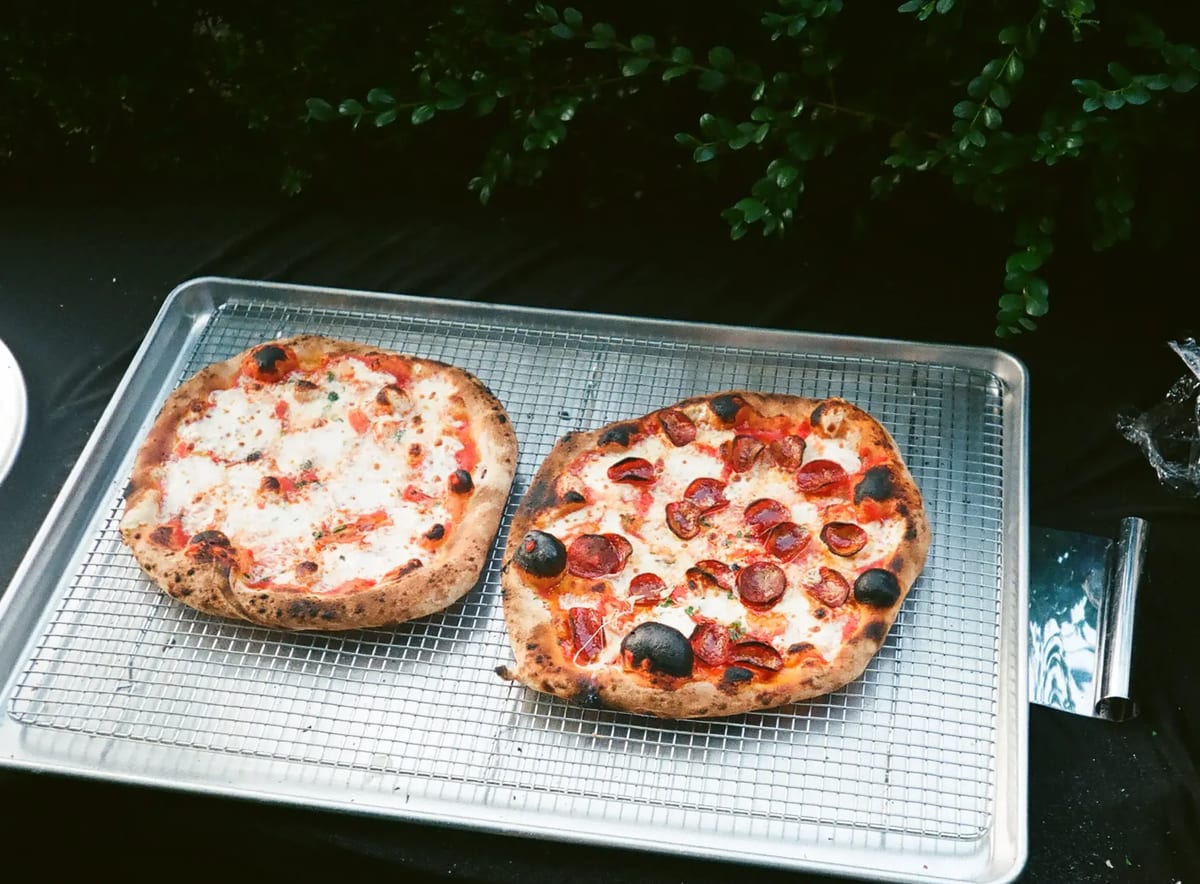 Two wood-fired pizzas on a steel tray on the truck's counter
